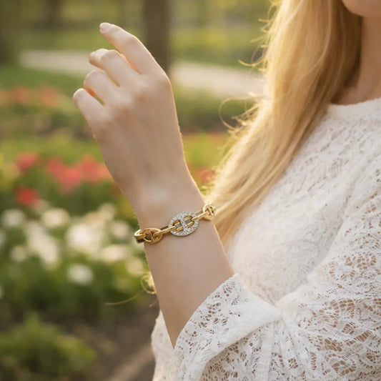 Woman wearing a gold bracelet with a blurred garden background