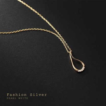 Gold necklace with a teardrop pendant on a black background
