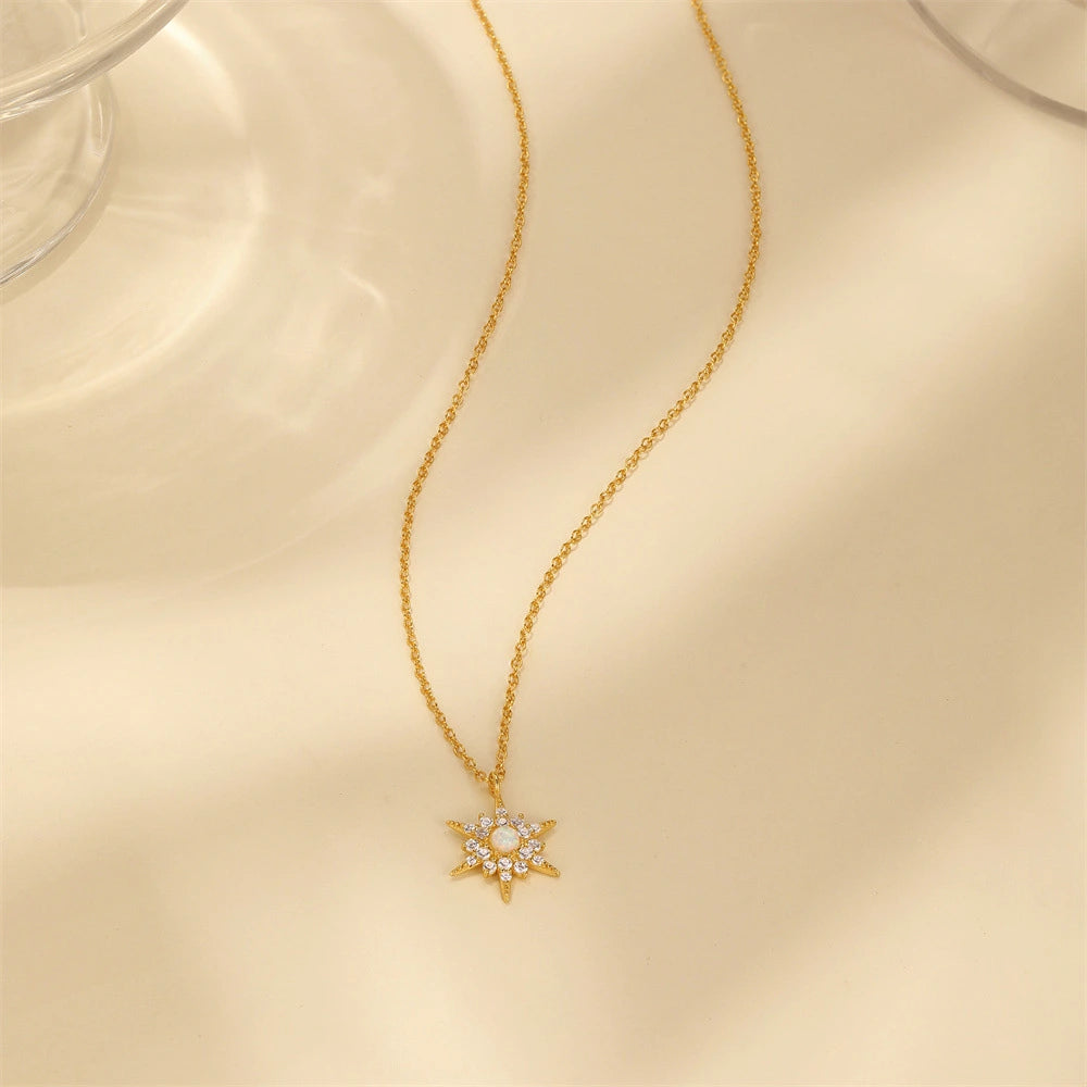 Gold necklace with a star-shaped pendant on a beige surface