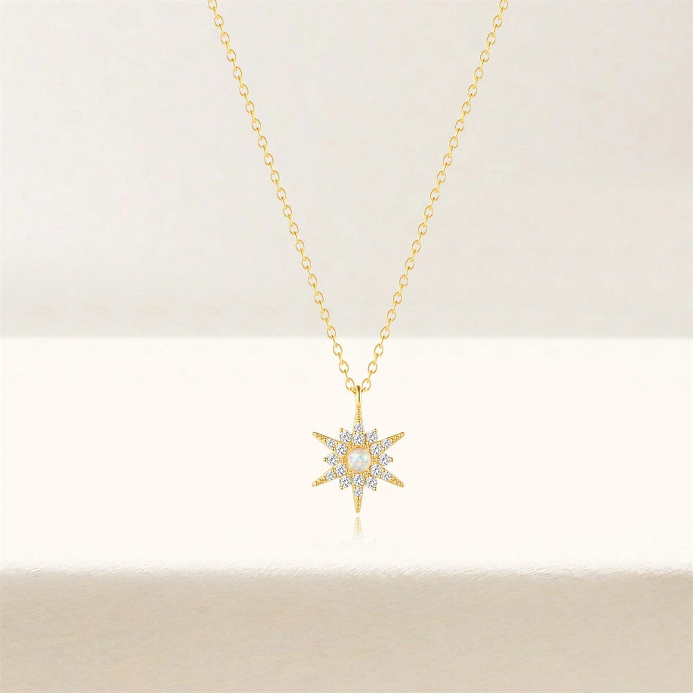 Gold necklace with a star-shaped pendant on a light beige background