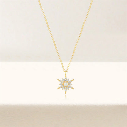 Gold necklace with a star-shaped pendant on a light beige background