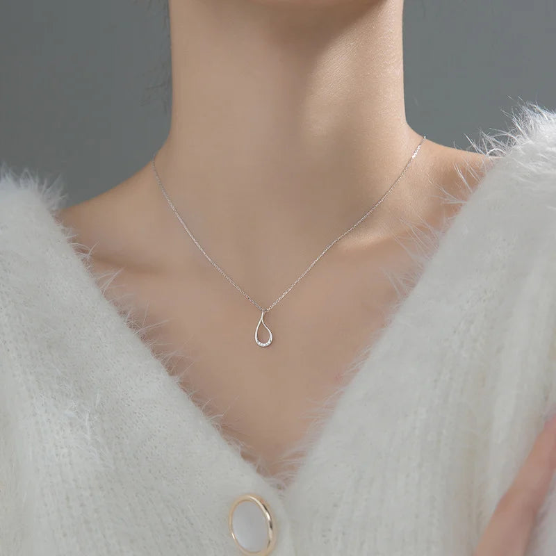Silver necklace with a teardrop pendant on a mannequin wearing a white fur coat.
