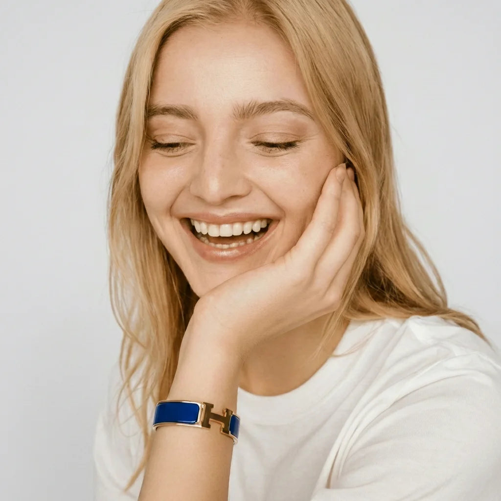 Woman with blonde hair smiling and wearing a blue bracelet on a light background