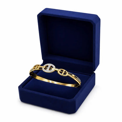 Gold bracelet with a diamond in a blue jewelry box on a white background