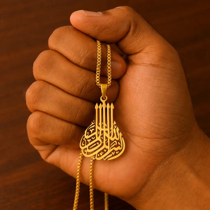 Gold necklace with a pendant held in a hand against a wooden background