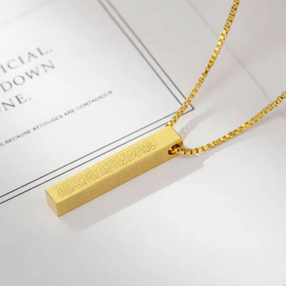 Gold necklace with a rectangular pendant on a light background