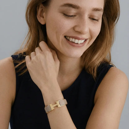 Woman wearing a gold bracelet on a plain background