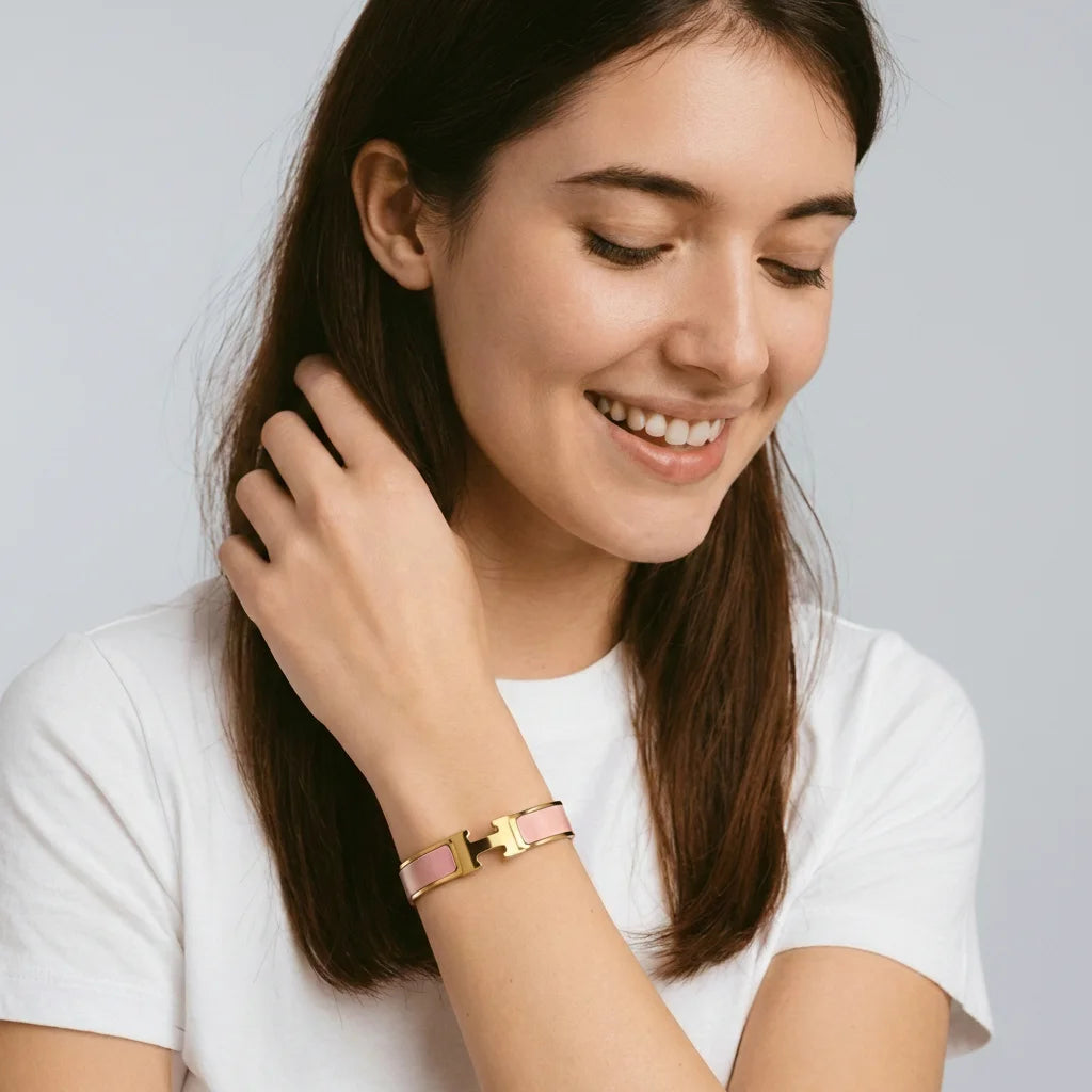 Woman wearing a gold bracelet on a plain background