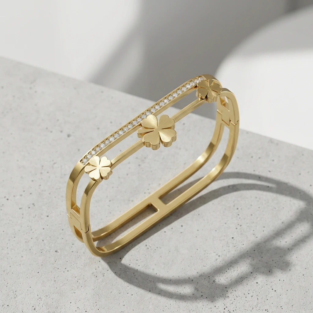 Gold bracelet with clover designs on a light gray surface