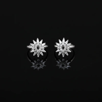 Star-shaped silver earrings with clear stones on a black background