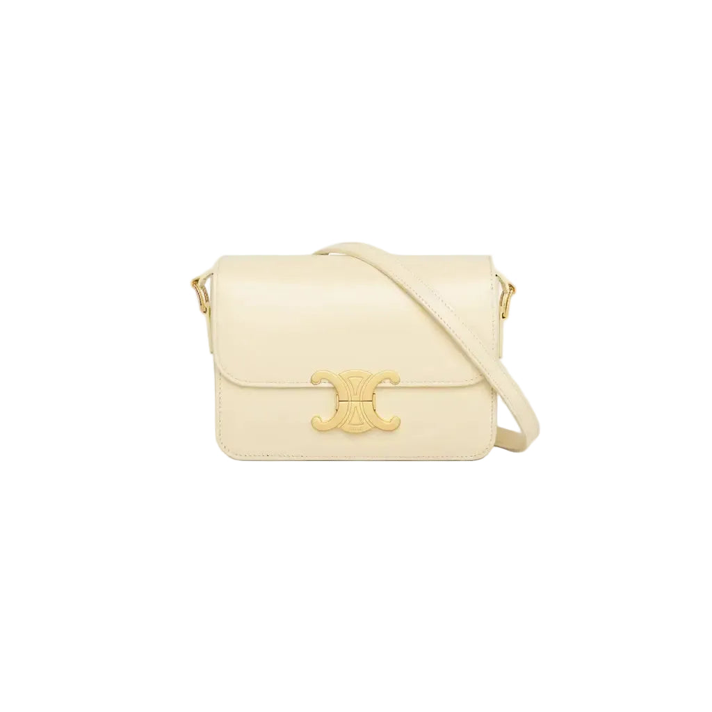 Cream-colored handbag with a gold emblem on a light gray background