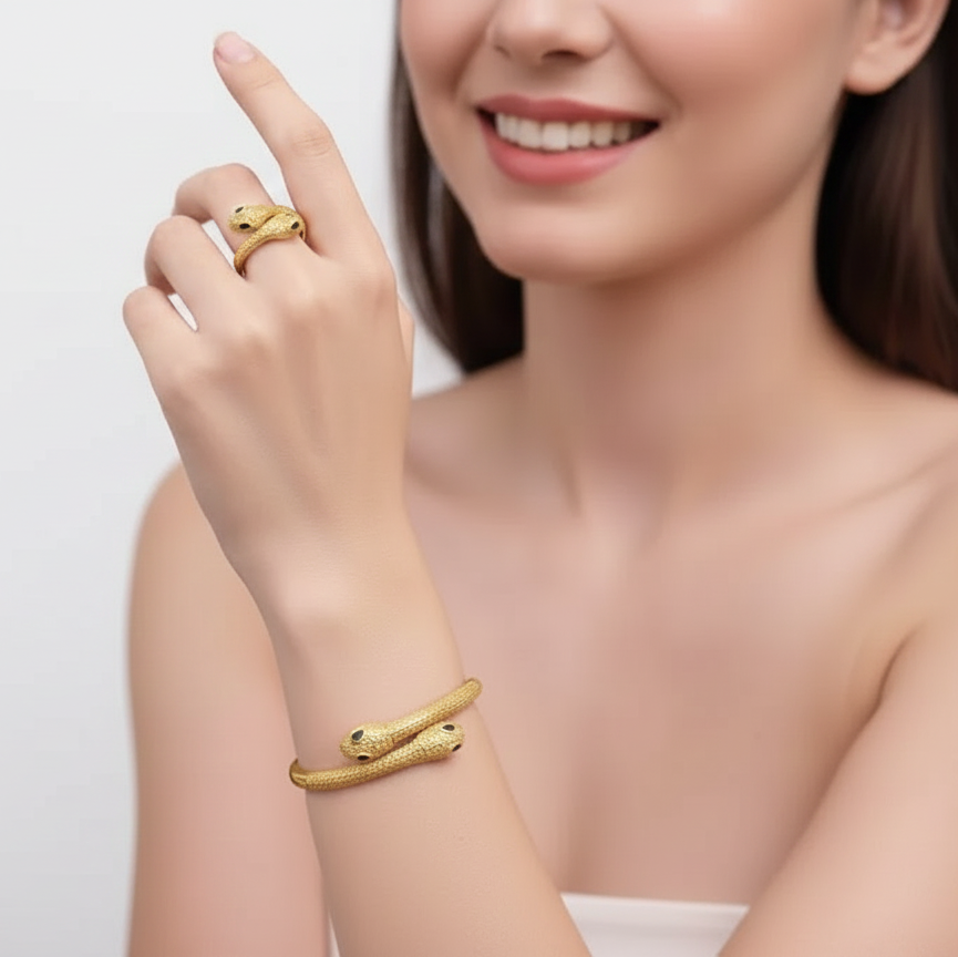 Woman wearing a gold snake bracelet and ring on a plain background