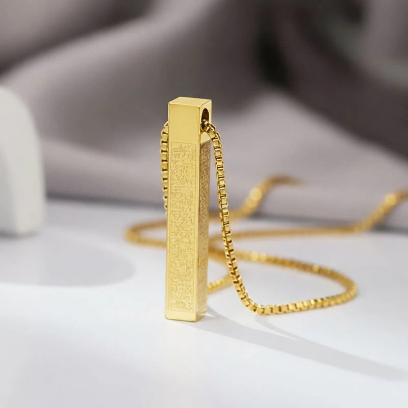 Gold pendant necklace on a light surface with a blurred background