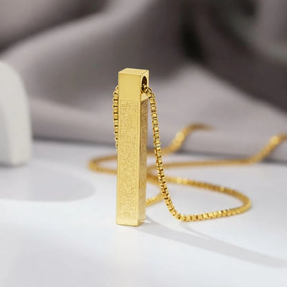 Gold pendant necklace on a light surface with a blurred background