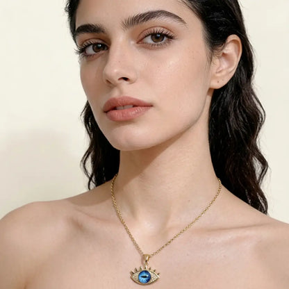 Woman wearing a gold necklace with an eye pendant on a beige background