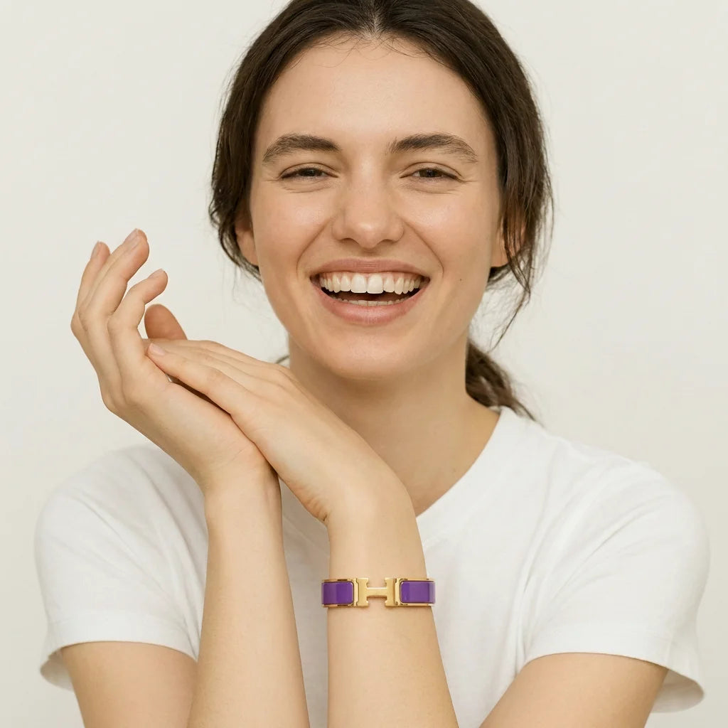 Woman wearing a gold and purple bracelet on a plain background