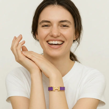 Woman wearing a gold and purple bracelet on a plain background
