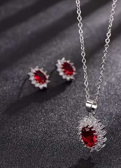 Silver jewelry set with red gemstones on a dark background