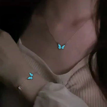 Person wearing a butterfly-shaped necklace and bracelet with a dark background