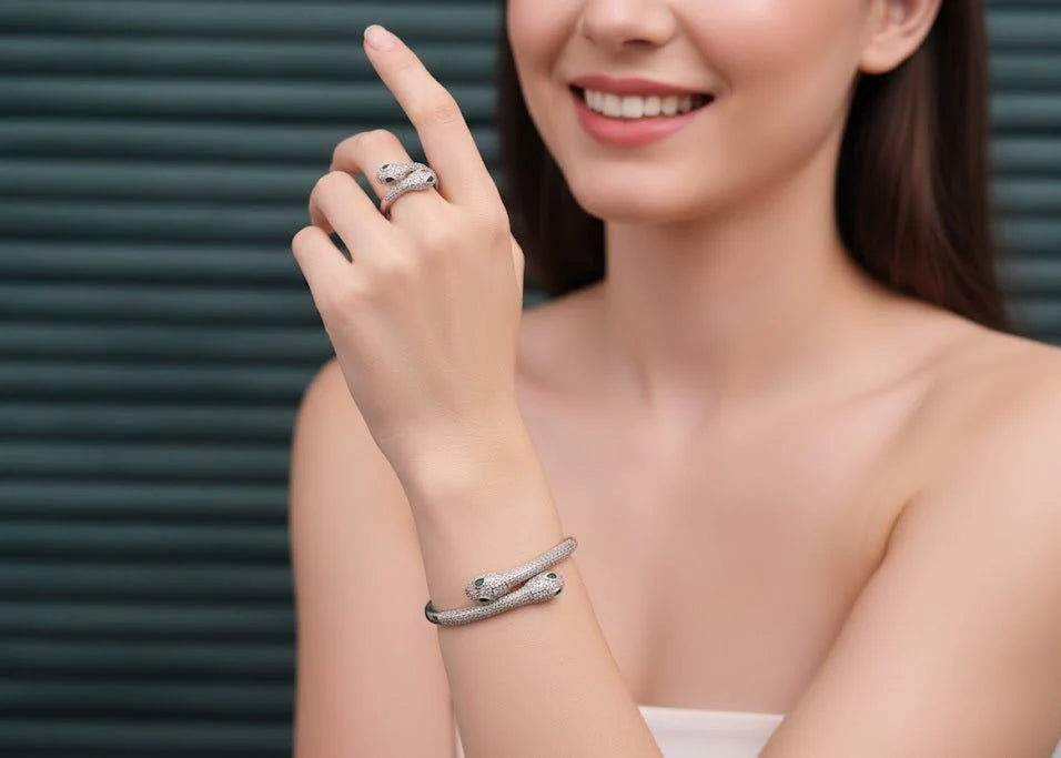Woman wearing a silver snake bracelet and ring on a plain background