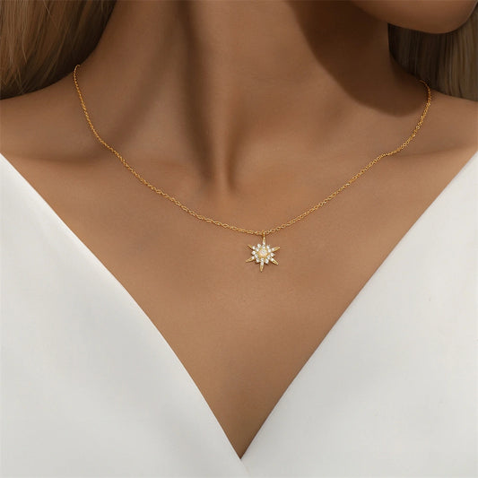 Gold necklace with a star-shaped pendant on a model wearing a white top.