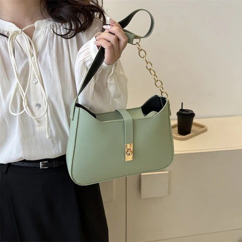 Person holding a light green handbag with a plain background