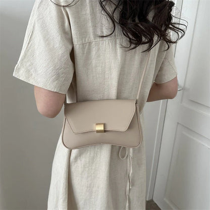 Person wearing a beige dress with a matching crossbody bag against a neutral background