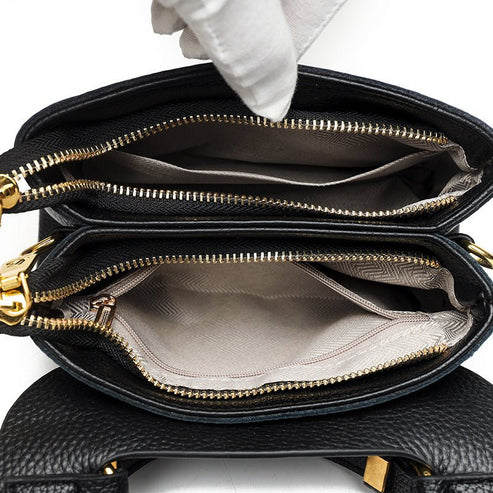 Black handbag with gold zippers on a white background