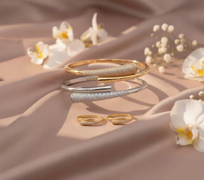 Gold and silver bracelets on a beige fabric background with flowers.