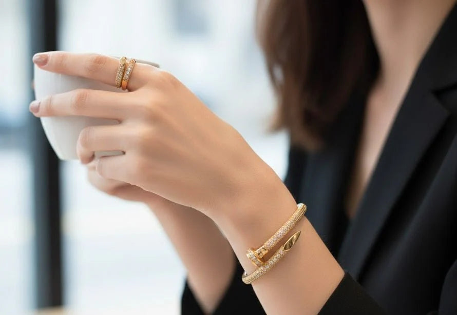 Person holding a white mug with gold bracelets on a blurred background