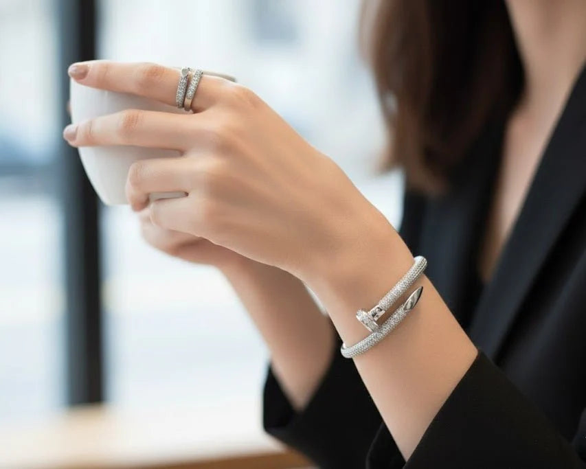 Person holding a white mug with jewelry on a blurred background