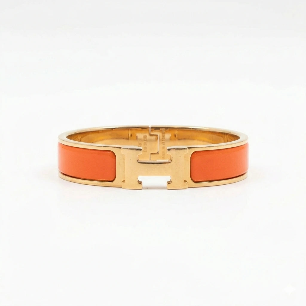 Gold bracelet with orange enameled C logo on a white background