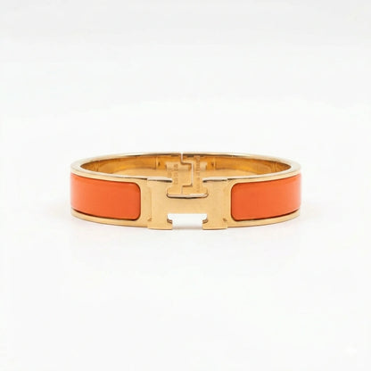 Gold bracelet with orange enameled C logo on a white background