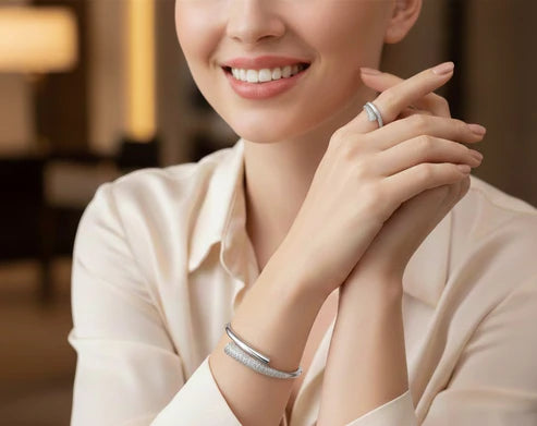 Woman wearing a silver ring and bracelet, smiling indoors.