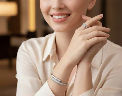 Woman wearing a silver ring and bracelet, smiling indoors.